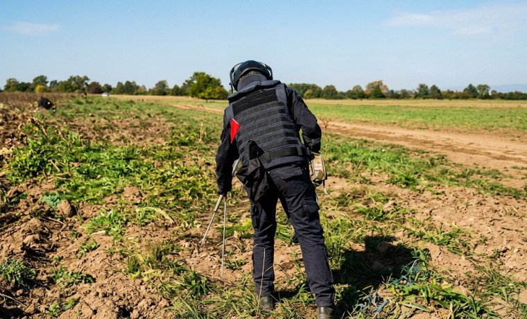 A bomb-disposal specialist scans a cultivated field for unexploded ordnance in Chechnya.